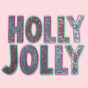 Puede incluir: Un parche festivo con las palabras "HOLLY JOLLY" en lentejuelas rosas y verdes con contornos blancos.