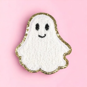 May include: A white fuzzy ghost with a gold glitter outline and a black embroidered smiling face.