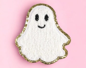 May include: A white fuzzy ghost with a gold glitter outline and a black embroidered smiling face.
