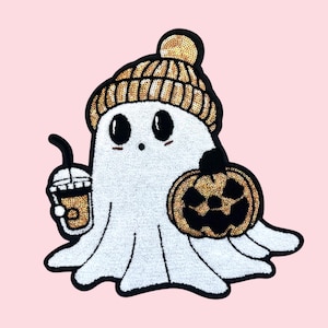 Op de afbeelding: Een wit spookvormig embleem met een gouden paillettenmuts en een zwarte en gouden pompoen. De geest houdt een koffiedrankje vast. De patch staat op een roze achtergrond. Halloween thema.