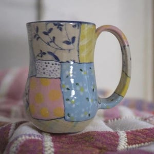 Pu&ograve; includere: Un set di tre tazze in ceramica con finitura opaca e macchiettata. Le tazze sono nei toni del crema, grigio chiaro e grigio scuro. Ogni tazza ha un design semplice e moderno e un manico arrotondato.