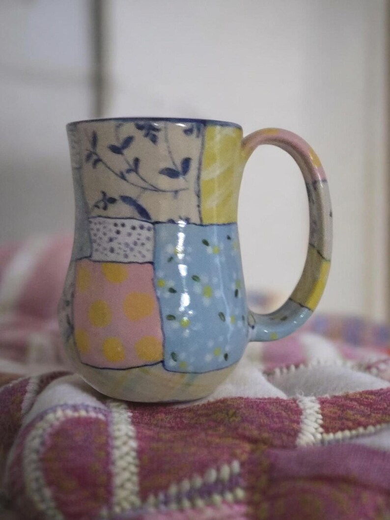 Pu&ograve; includere: Un set di tre tazze in ceramica con finitura opaca e macchiettata. Le tazze sono nei toni del crema, grigio chiaro e grigio scuro. Ogni tazza ha un design semplice e moderno e un manico arrotondato.