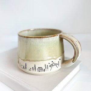 handmade ceramic camping/outdoor images around base, creamy tan color top and no glaze on the bottom