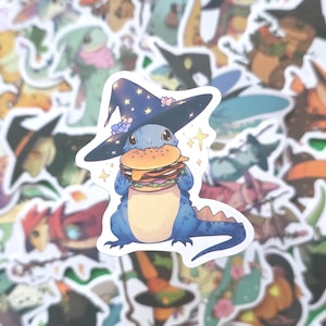 May include: A sticker featuring a blue cartoon lizard wearing a witch hat and holding a burger. The hat is navy blue with gold stars and pink flowers. The sticker is surrounded by other fantasy-themed stickers.