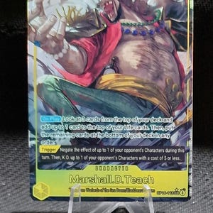 Può includere: Una carta collezionabile One Piece raffigurante Marshall D. Teach con un livello di potenza di 10000. La carta mostra un'illustrazione dinamica del personaggio con camicia rossa e pantaloni verdi, con testo sulle abilità di gioco.
