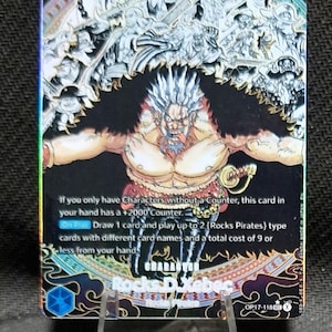 May include: A One Piece trading card featuring Rocks D. Xebec with spiky hair, a black fur collar, and a sword. The card displays the text: If you only have Characters without a Counter, this card in your hand has a +2000 Counter. On Play: Draw 1 card.