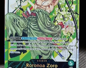 May include: A trading card featuring Roronoa Zoro from the One Piece series. The card has a green and yellow background with the character in a dynamic pose. The card displays the text "5000" and "/600". The card is displayed on a clear plastic stand.