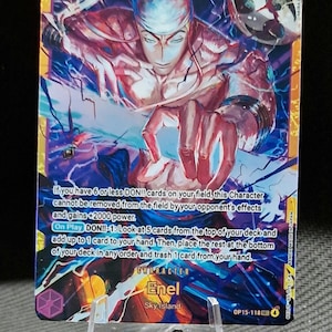 May include: A collectible trading card featuring Enel from Sky Island. The card has a vibrant design with a character illustration and text detailing game effects. The card is held by a clear plastic stand.