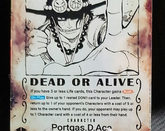 May include: A trading card featuring a character illustration of Portgas D. Ace from the Whitebeard Pirates. The card has the word "WANTED" at the top, with the text "DEAD OR ALIVE" below the illustration. The card is displayed on a clear plastic stand.