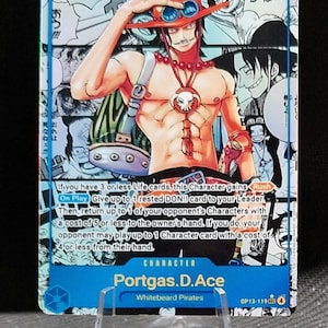Puede incluir: Carta coleccionable con Portgas D. Ace de los Whitebeard Pirates. La carta tiene un fondo azul con una ilustración de personaje y texto japonés. El personaje lleva un sombrero naranja y un colgante de calavera.