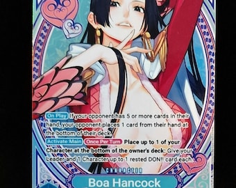 May include: A trading card featuring Boa Hancock from the One Piece series. The card has a blue and pink design with the character's image and game text. The card is displayed on a clear plastic stand.