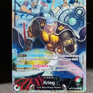 Op de afbeelding: Een ruilkaart met Krieg van de East Blue/Krieg Pirates. De kaart toont een kleurrijke illustratie van Krieg, met tekst zoals "LEADER" en "5000". De kaart wordt gepresenteerd op een transparante standaard.
