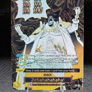 Può includere: Una carta collezionabile One Piece intitolata Zehahahahaha! con un'illustrazione in bianco e nero di Marshall D. Teach con le braccia alzate. La carta ha uno sfondo giallo e nero, testo sulle regole di gioco e un costo di 8 nell'angolo.