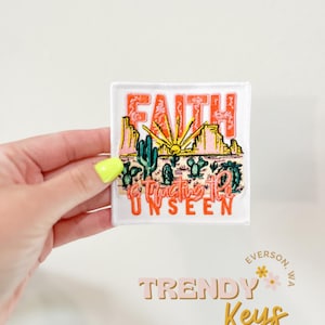 May include: White embroidered patch with a desert landscape and the text "Faith is trusting the unseen".