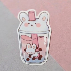 May include: A sticker of a pink and white boba tea with a white bunny rabbit inside. The boba tea has a pink straw and a white lid with bunny ears.