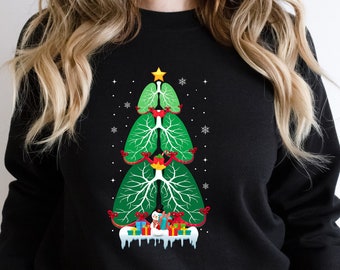 May include: Black sweatshirt with a green, red, and white Christmas tree design featuring a stylized lung with ornaments. The tree is decorated with red and white ornaments and a snowman.