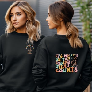 May include: Black sweatshirt with a colorful graphic on the back that says "It's what's on the inside that counts" and a smaller graphic on the front that says "Sonographer".