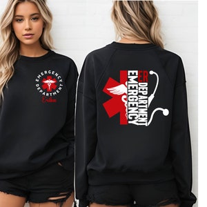May include: Black sweatshirt with a red medical symbol and the text "ER Department Emergency" on the back. The front of the sweatshirt has a smaller version of the symbol with the text "Emergency Department" and the name "Erika".