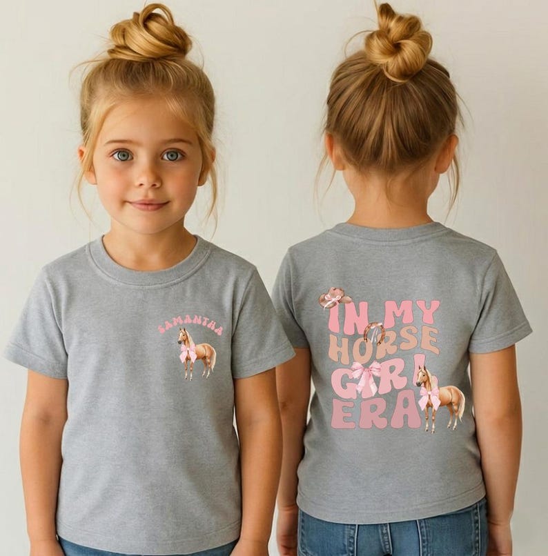 May include: Two children wearing gray t-shirts with horse-themed designs. The front of one shirt says "Samantha" above a horse with a pink bow. The back of the other shirt says "In My Horse Girl Era" with horse graphics.
