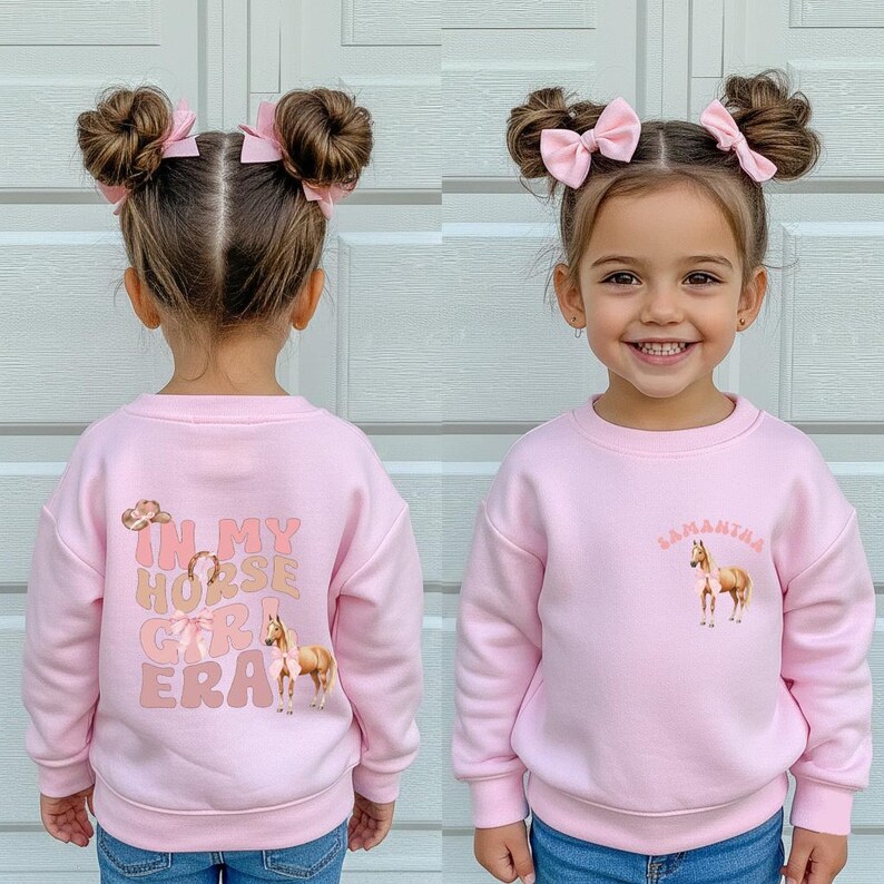 May include: A pink sweatshirt with the text "IN MY HORSE GIRL ERA" and a horse graphic on the back. The front of the sweatshirt has the name "Samantha" and a horse graphic. The child is wearing blue jeans.