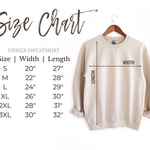May include: A beige unisex sweatshirt displayed on a wooden hanger. The image features a size chart with measurements in inches for width and length, ranging from size small to 3XL. The text "Size Chart" is at the top.