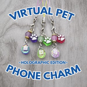 May include: Several holographic phone charms with paw print and star designs. The charms are in various colors, including purple, green, and pink. The text "VIRTUAL PET" and "PHONE CHARM" are displayed in blue, with "~HOLOGRAPHIC EDITION~" below.