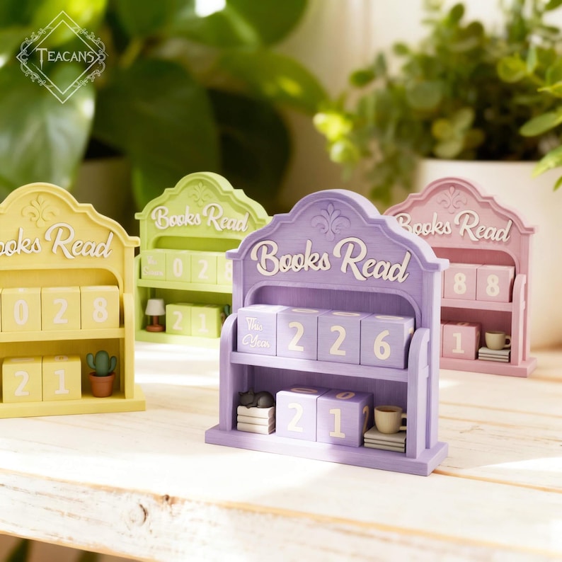 Puede incluir: Una colecci&oacute;n de calendarios de lectura de libros de madera en colores pastel. Cada calendario muestra las palabras "Books Read" y presenta una estanter&iacute;a con bloques numerados. Los calendarios son de color amarillo, verde, morado y rosa, con peque&ntilde;os objetos decorativos.