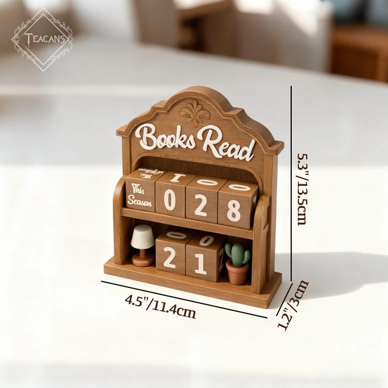 Puede incluir: Un calendario de escritorio de madera con las palabras "Books Read" en escritura blanca. El calendario muestra los n&uacute;meros "028" y "21" en bloques giratorios. Incluye una peque&ntilde;a l&aacute;mpara y un cactus en maceta. El calendario mide 11,4 cm de ancho, 13,5 cm de alto y 3 cm de profundidad.