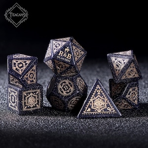Pu&ograve; includere: Un set di sette dadi blu e dorati con un motivo a cielo stellato. I dadi sono di varie forme, tra cui una piramide, un cubo e un dodecaedro. I dadi sono incisi con numeri e simboli, tra cui un occhio e una corona. I dadi sono personalizzati con le iniziali "R&B" e la data "05.24.2024".