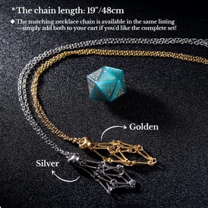 May include: A silver and gold necklace with a geometric pendant, displayed with a teal blue, multi-sided die. The chain length is 19 inches (48cm). The image is on a dark background.