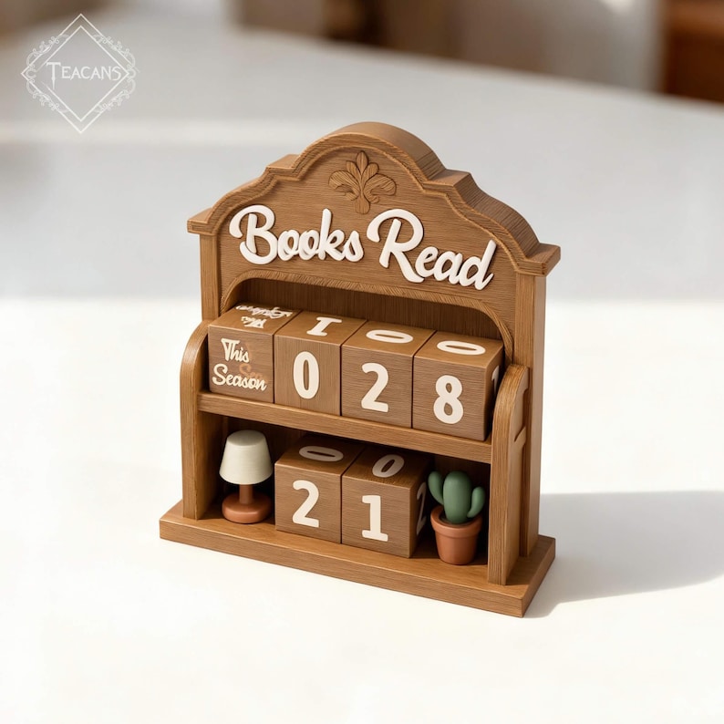 Puede incluir: Un calendario de madera "Books Read" con bloques de n&uacute;meros giratorios. Los bloques muestran los n&uacute;meros "028" y "21". Una peque&ntilde;a l&aacute;mpara y un cactus en maceta est&aacute;n en el estante. Tambi&eacute;n se ve el texto "This Season".