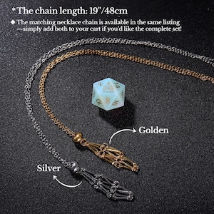May include: Two necklace chains, one silver and one gold, with a decorative tassel at the end. The chains are displayed against a black background with a light blue and gold 20-sided die in the centre. The chain length is 19 inches or 48 centimetres.