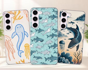 May include: Three phone cases with marine life designs. One case features a blue whale shark and coral on a white background. Another has a pattern of sharks on a light blue background. The third case shows a whale shark and a seascape.