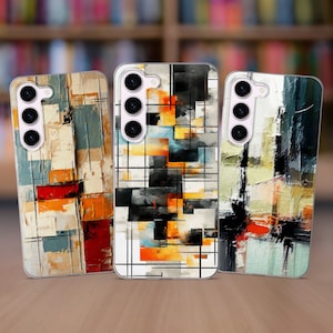 May include: Three phone cases with abstract geometric designs. The cases are clear and show off the colorful designs. The designs are in shades of orange, yellow, blue, black, and white.