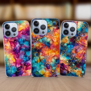 May include: Three iPhone cases with a colorful abstract design featuring a swirling pattern of blue, purple, yellow, and orange. The design resembles a watercolor painting with gold accents.