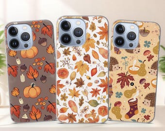 May include: Three phone cases with autumn-themed designs. One case features pumpkins, leaves, and acorns on a brown background. Another has a white background with leaves and berries. The third case has hedgehogs, pears, and leaves.