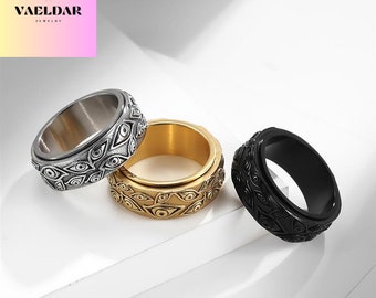 May include: Three spinning rings with an eye design. The rings are silver, gold, and black.