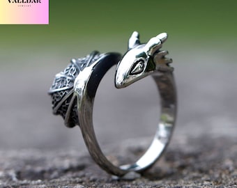 Op de afbeelding: Een zilveren drakenring met een gedetailleerd ontwerp. De kop van de draak is om de band van de ring gewikkeld.