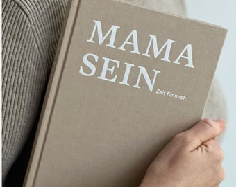 May include: A beige linen-covered journal with the text "MAMA SEIN Zeit für mich" in white lettering.