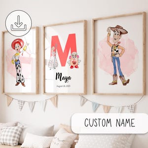 Può includere: Tre stampe incorniciate con personaggi dei cartoni animati. Una stampa mostra una cowgirl, un'altra ha una grande lettera rossa "M" con personaggi e il nome "Maya", e la terza raffigura un cowboy. Le stampe sono in cornici di legno e sono appese sopra un divano.