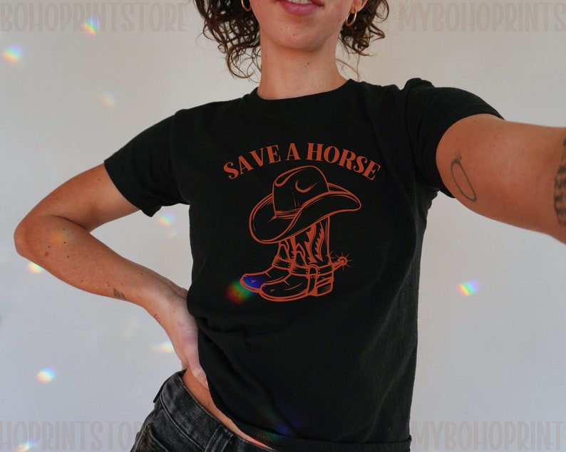 May include: Black t-shirt with a graphic of a cowboy boot and hat in orange. The text "SAVE A HORSE" is printed in orange above the graphic.
