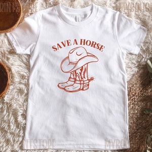 May include: White t-shirt with a red graphic of a cowboy hat and boots. The text "Save a Horse" is above the graphic.