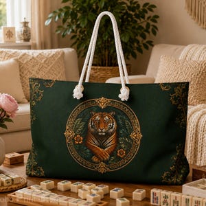 May include: A dark green tote bag featuring a central circular emblem with a tiger illustration surrounded by gold filigree. The bag has two white rope handles and gold decorative corner accents. The text My Boho Print Store is visible.
