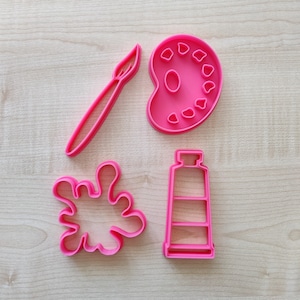Può includere: Quattro tagliabiscotti in plastica rosa a forma di pennello, tavolozza di colori, tubo di vernice e uno schizzo di vernice.