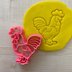 May include: Pink plastic cookie cutter shaped like a rooster. The cutter is shown next to a yellow piece of modeling clay with an impression of the rooster.