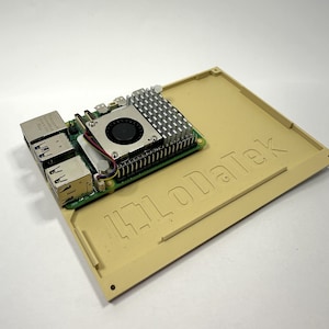 以下が含まれることがあります： ベージュのコンピューターケースに「Hi-LoData」という文字が印刷されています。冷却ファンと複数のUSBポートが付いた小さな緑色の回路基板がケース内に取り付けられています。