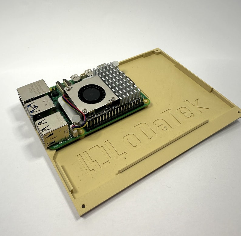 以下が含まれることがあります： ベージュのコンピューターケースに「Hi-LoData」という文字が印刷されています。冷却ファンと複数のUSBポートが付いた小さな緑色の回路基板がケース内に取り付けられています。