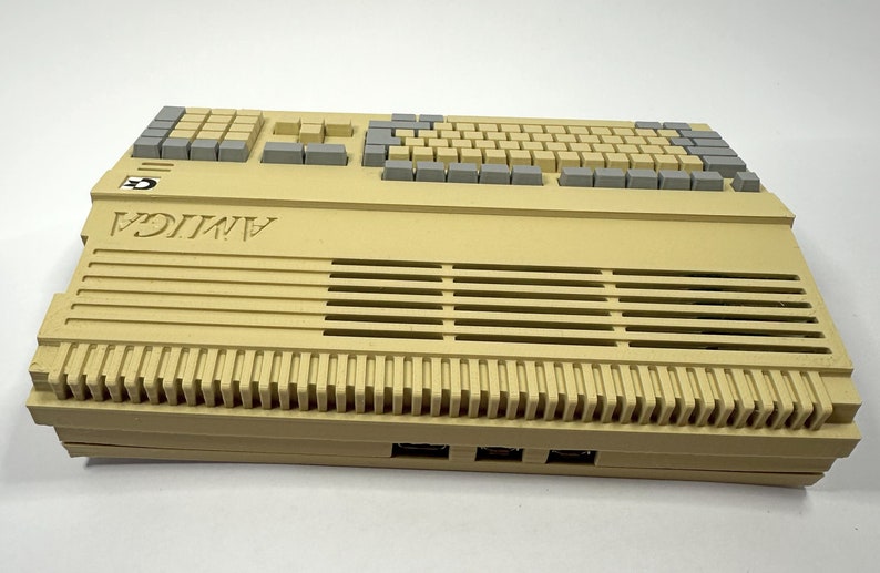 以下が含まれることがあります： 前面に「AMIGA」と印刷されたグレーのキーボードが付いたベージュのAmigaコンピューター