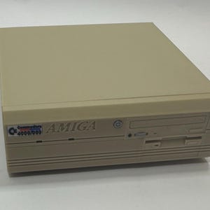 May include: Beige Commodore Amiga 4000/060 computer. The front of the computer has a disk drive slot, a CD-ROM drive slot, and a power button. The Amiga logo is visible on the front of the computer.