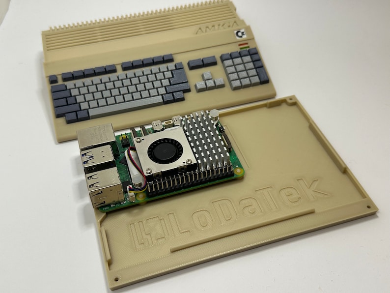 以下が含まれることがあります： ベージュのAmigaコンピューターケースとキーボード、緑色の回路基板にファンとヒートシンクが搭載されています。回路基板には「HiLoDaTek」とラベルが貼られています。